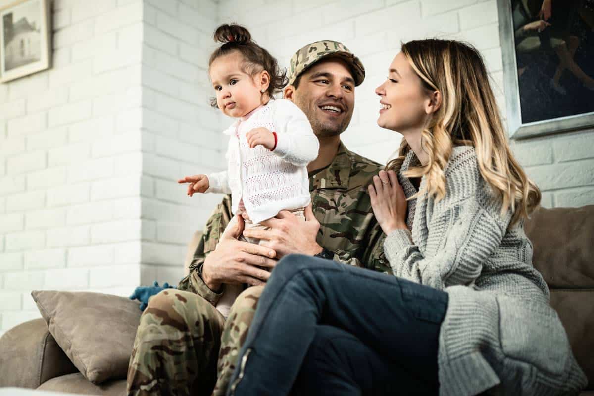 Family sitting together indoors with a parent in military uniform holding a young child