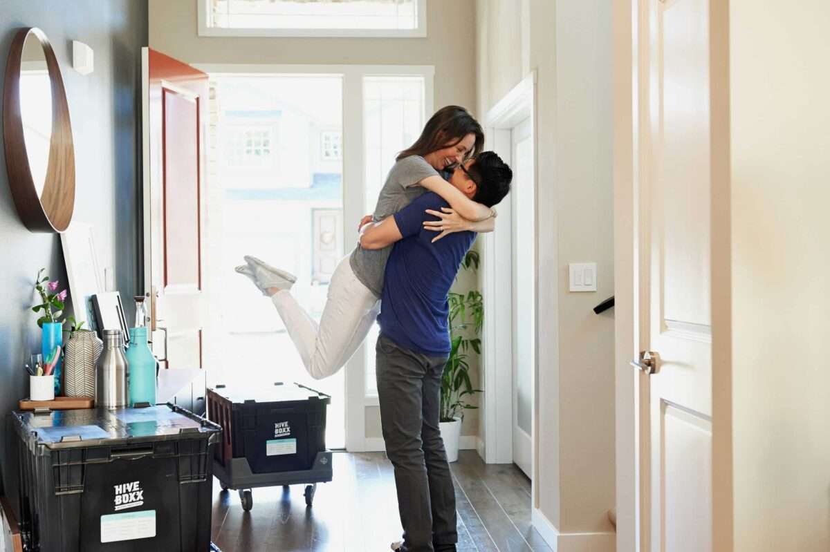 Couple embracing in the entryway of a new home with moving boxes nearby