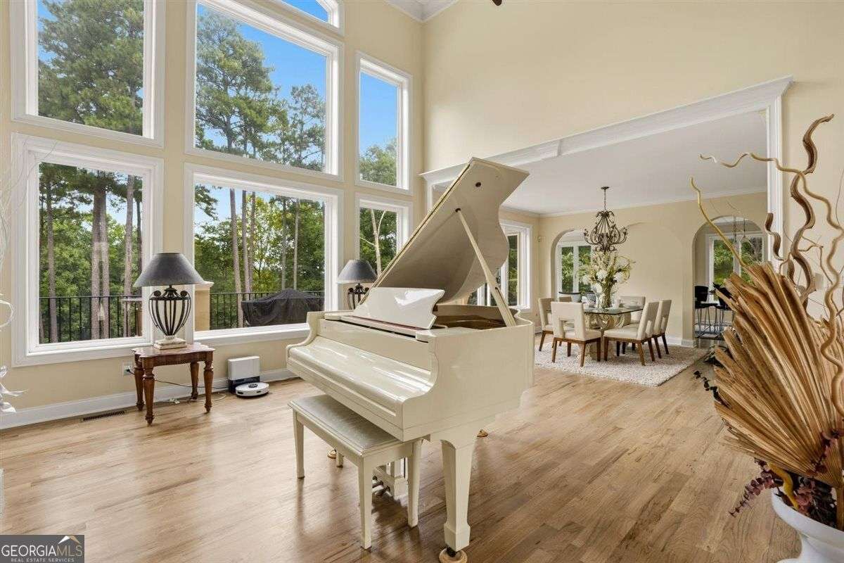 Luxury living room with grand piano and floor-to-ceiling windows at 124 Fairway Run in Forsyth, GA
