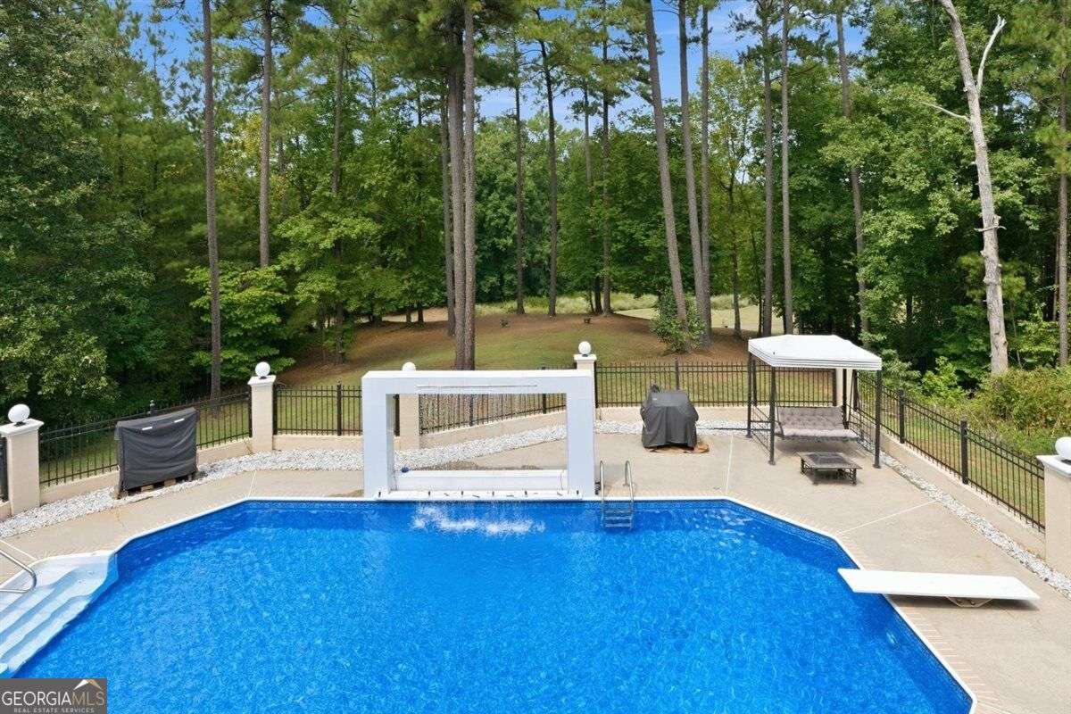Backyard swimming pool with waterfall feature and wooded views at 124 Fairway Run in Forsyth, Georgia
