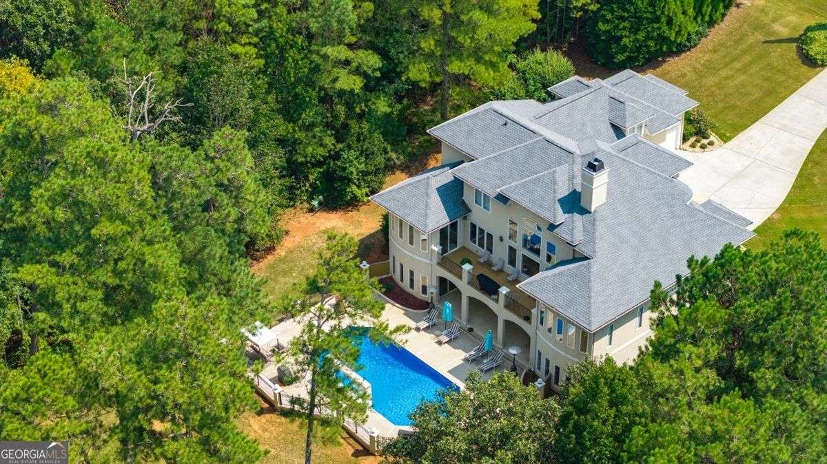 Aerial view of 124 Fairway Run in Forsyth, Georgia, featuring a private backyard swimming pool surrounded by mature trees