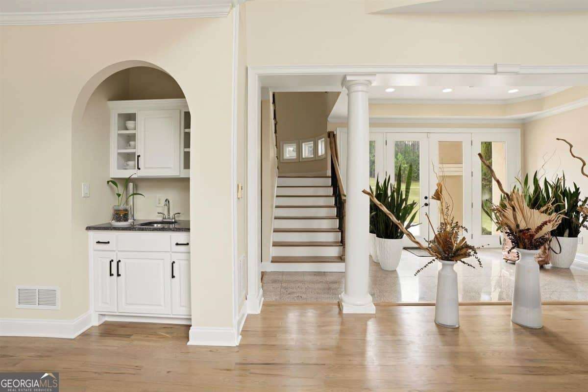 Luxury home interior with wet bar, staircase, and bright living area at 124 Fairway Run in Forsyth, GA
