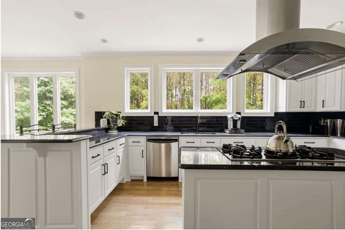 Luxury kitchen with white cabinetry, black countertops, and large windows at 124 Fairway Run in Forsyth, GA