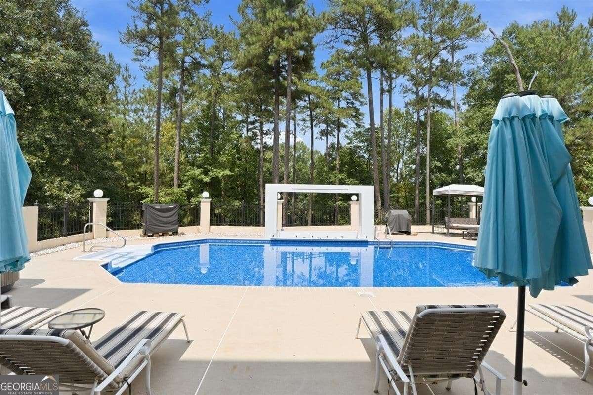 In-ground swimming pool with lounge chairs and wooded surroundings at 124 Fairway Run in Forsyth, GA